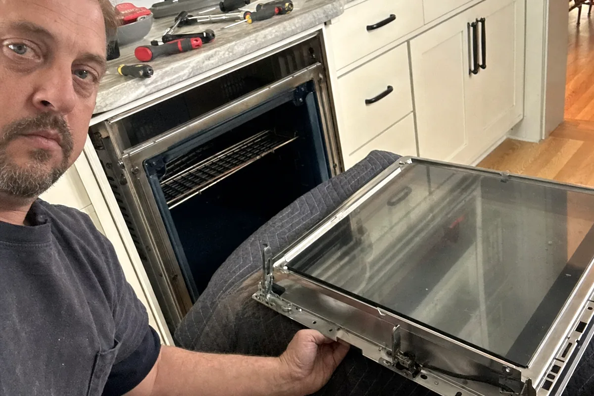 An oven door stripped back to its frame partway through a routine repair